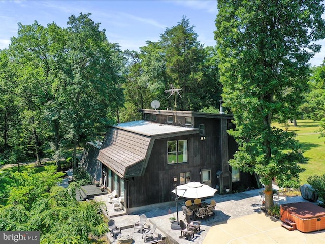  - rear view of house with a patio, a hot tub, and view of scattered trees
