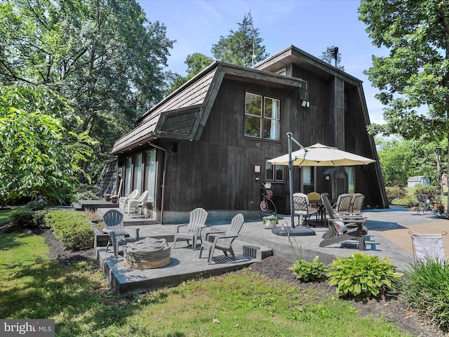  - back of house with a fire pit, a patio, and a gambrel roof