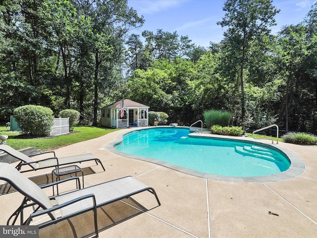  - outdoor pool featuring a storage structure, a patio, an outbuilding, and view of scattered trees