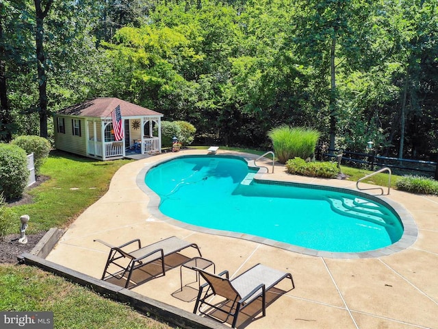  - swimming pool featuring an outdoor structure, a patio, a storage structure, a diving board, and a view of trees