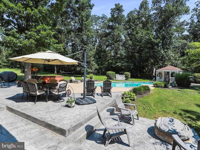  - view of patio featuring an outdoor pool, an outbuilding, view of scattered trees, and outdoor dining area