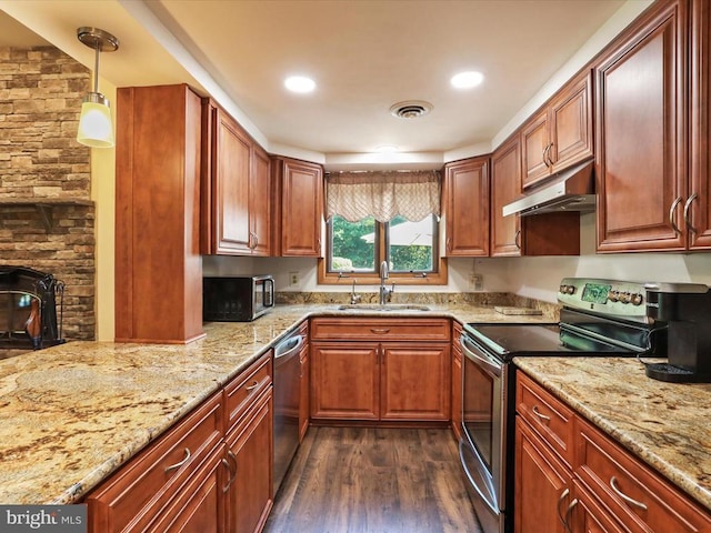  - kitchen with appliances with stainless steel finishes, under cabinet range hood, dark wood-style floors, light stone countertops, and decorative light fixtures