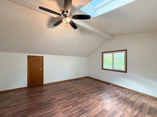 bonus room with a skylight, baseboards, dark wood finished floors, a ceiling fan, and a textured ceiling