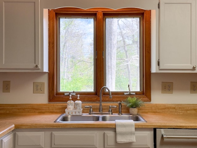 kitchen with a sink, dishwasher, light countertops, and white cabinets