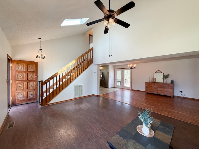 unfurnished living room with a chandelier, high vaulted ceiling, wood finished floors, a ceiling fan, and stairs