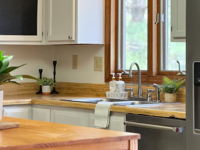 kitchen featuring dishwasher, a sink, and white cabinets