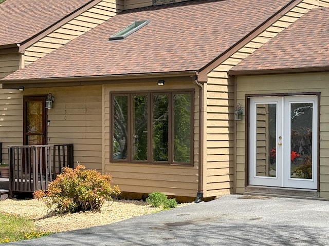 view of property exterior with french doors and a shingled roof