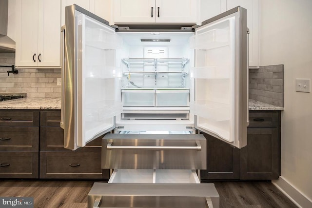 - kitchen with dark wood finished floors, refrigerator, white cabinetry, decorative backsplash, and light stone countertops