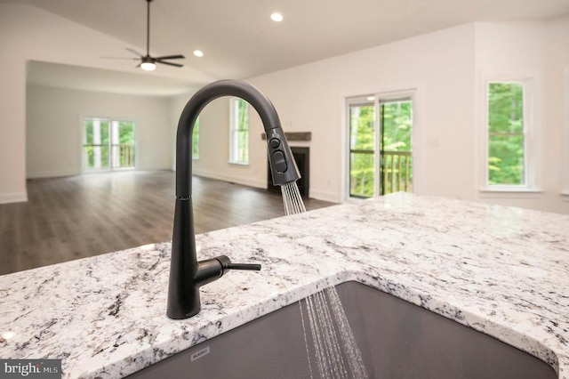  - kitchen view of wood finished floors, recessed lighting, light stone counters, and a ceiling fan