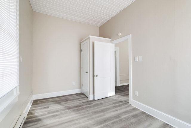 empty room with baseboard heating and light wood-type flooring