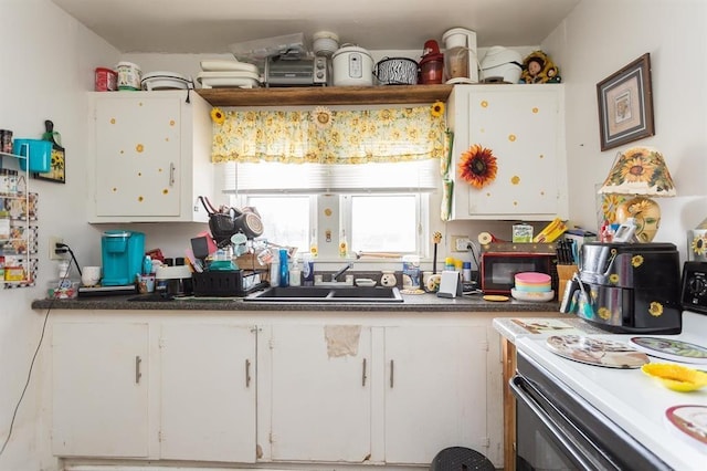 kitchen with white cabinetry, sink, and electric range