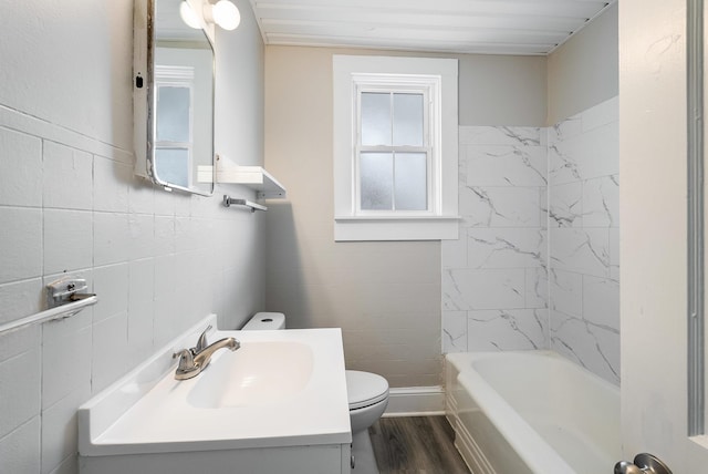 bathroom featuring wood-type flooring, tile walls, vanity, toilet, and a bath