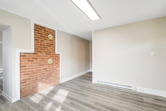 unfurnished room featuring a baseboard radiator, brick wall, and light hardwood / wood-style flooring