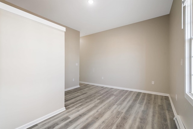 empty room featuring a baseboard heating unit and light wood-type flooring