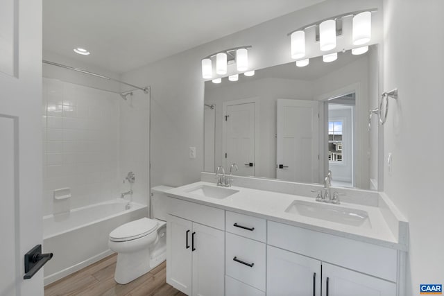 full bath featuring a sink, double vanity, toilet, and wood finished floors