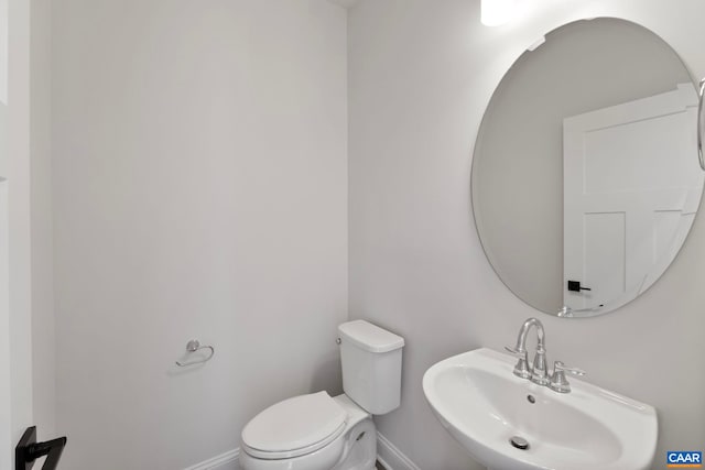bathroom with a sink, toilet, and baseboards