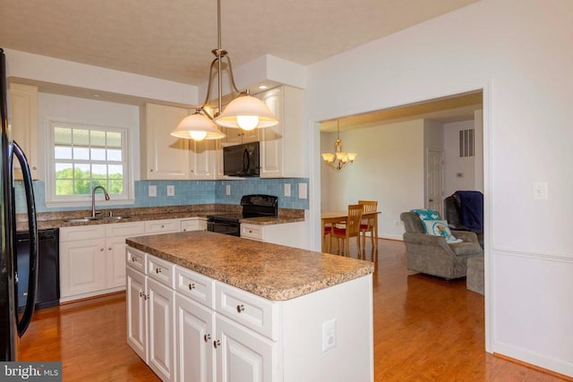7204 Morris Rd, Spotsylvania, VA 22551 - kitchen with black appliances, a sink, a chandelier, light wood-style flooring, and white cabinets