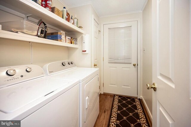 laundry room featuring washing machine and dryer, ornamental molding, and wood finished floors