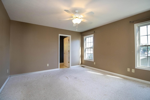 empty room with light colored carpet, ceiling fan, and baseboards