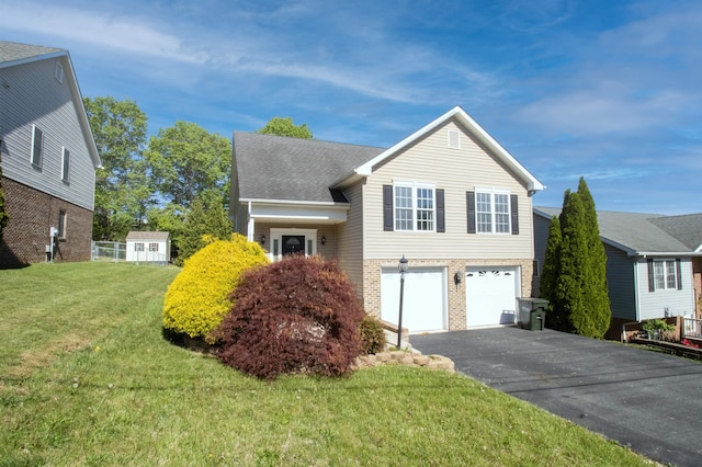 split level home with asphalt driveway, a garage, brick siding, and a front lawn