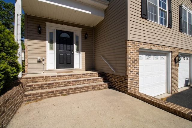 doorway to property with brick siding, an attached garage, and asphalt driveway