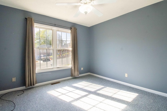 carpeted empty room with ceiling fan and baseboards