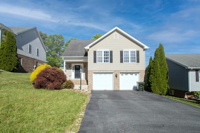 tri-level home featuring driveway, a garage, brick siding, and a front lawn