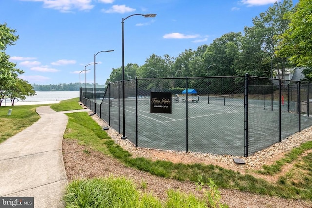 view of tennis court with a water view