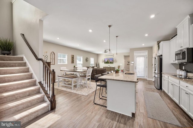 kitchen featuring appliances with stainless steel finishes, a sink, white cabinetry, wood finished floors, and recessed lighting