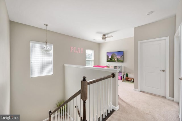 hallway with an upstairs landing, carpet flooring, and baseboards