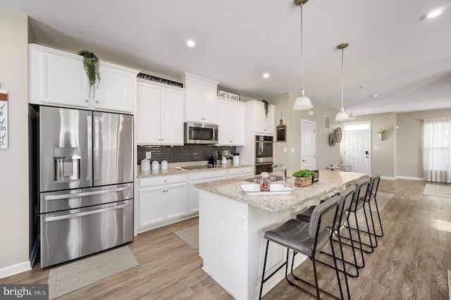 kitchen featuring stainless steel appliances, baseboards, a center island with sink, white cabinetry, and recessed lighting