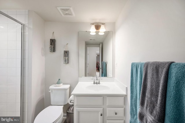 bathroom featuring toilet, vanity, and tiled shower