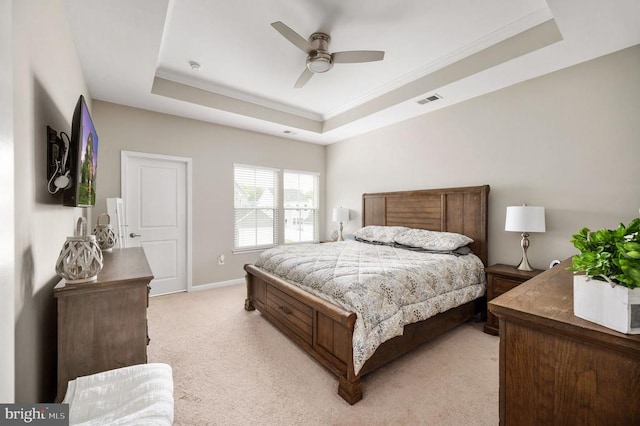 bedroom featuring a tray ceiling, light colored carpet, crown molding, a ceiling fan, and baseboards