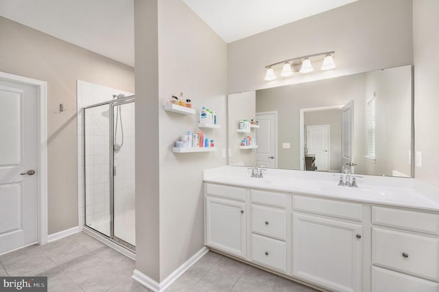 bathroom featuring a stall shower, tile patterned flooring, double vanity, and baseboards