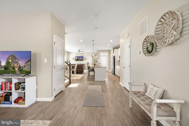 hall featuring light wood-type flooring, baseboards, and recessed lighting