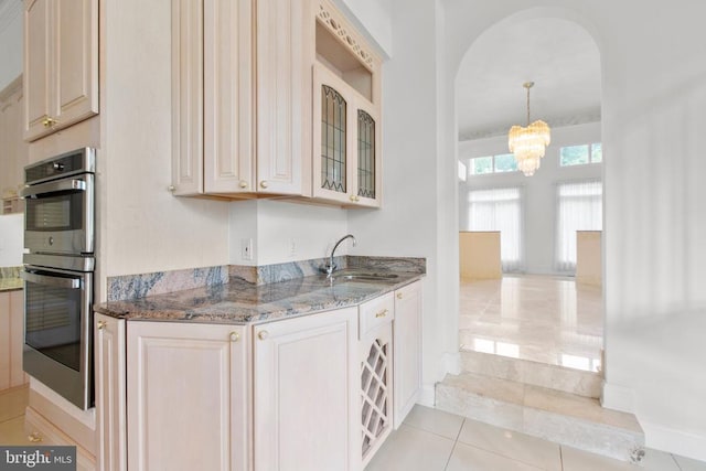 3714 Fairways Ct, Fredericksburg, VA 22408 - kitchen with double oven, a chandelier, stone countertops, arched walkways, and glass insert cabinets