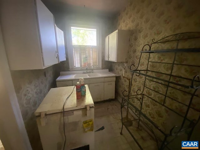 5367 James Madison Hwy, Fork Union, VA 23055 - kitchen featuring wallpapered walls, white cabinetry, light countertops, and a sink