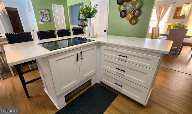 6603 Farmstead Ln, Fredericksburg, VA 22407 - kitchen with black electric cooktop, wood finished floors, light countertops, and white cabinets