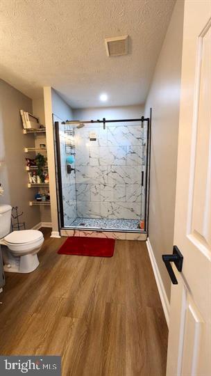 6603 Farmstead Ln, Fredericksburg, VA 22407 - full bath featuring toilet, a marble finish shower, wood finished floors, a textured ceiling, and baseboards