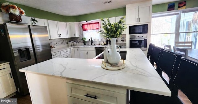 6603 Farmstead Ln, Fredericksburg, VA 22407 - kitchen featuring black appliances, a kitchen island with sink, light stone countertops, a sink, and white cabinetry