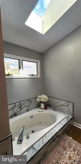 6603 Farmstead Ln, Fredericksburg, VA 22407 - full bathroom featuring a skylight, wood finished floors, a whirlpool tub, and baseboards