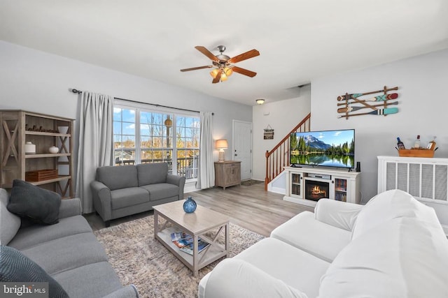 living area with wood finished floors, ceiling fan, stairway, and baseboards