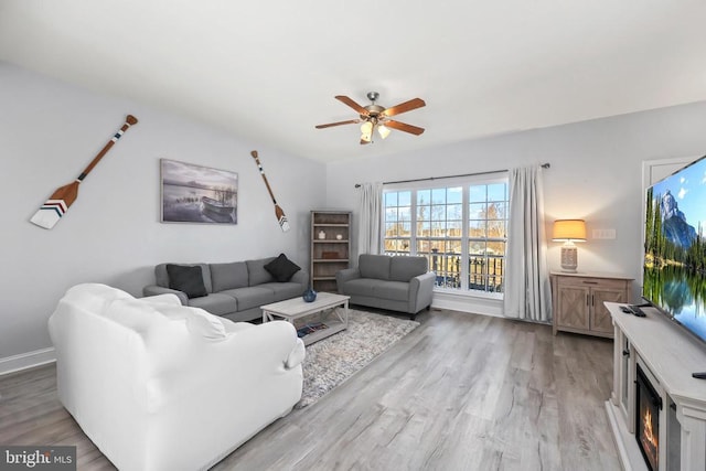 living area with ceiling fan, light wood finished floors, and baseboards