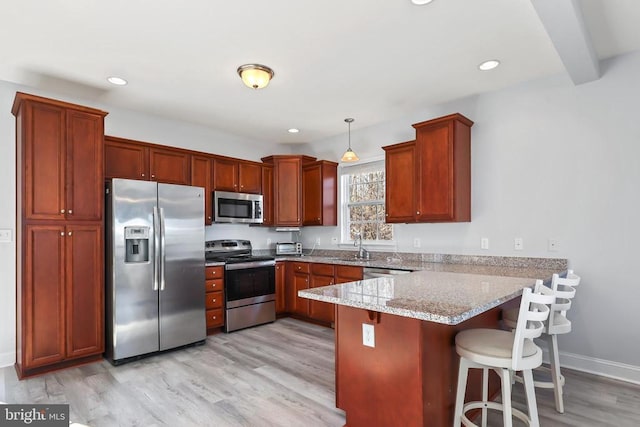 kitchen with appliances with stainless steel finishes, a peninsula, light wood-style flooring, a kitchen bar, and light stone counters