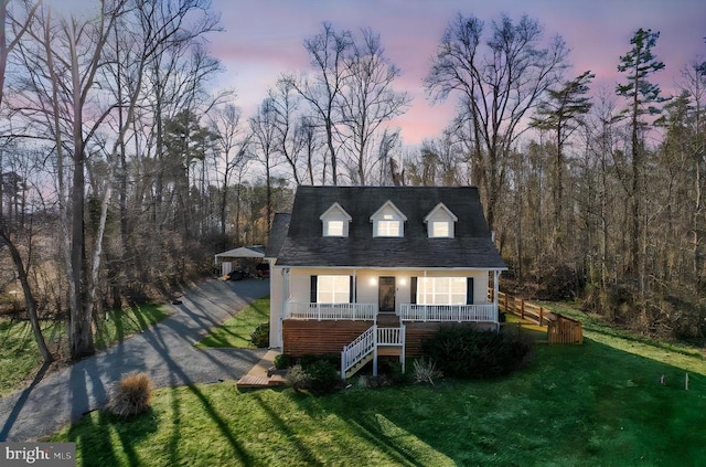 cape cod house featuring covered porch, stairway, driveway, and a front lawn