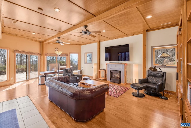 living area featuring light wood finished floors, wood ceiling, a ceiling fan, a glass covered fireplace, and recessed lighting
