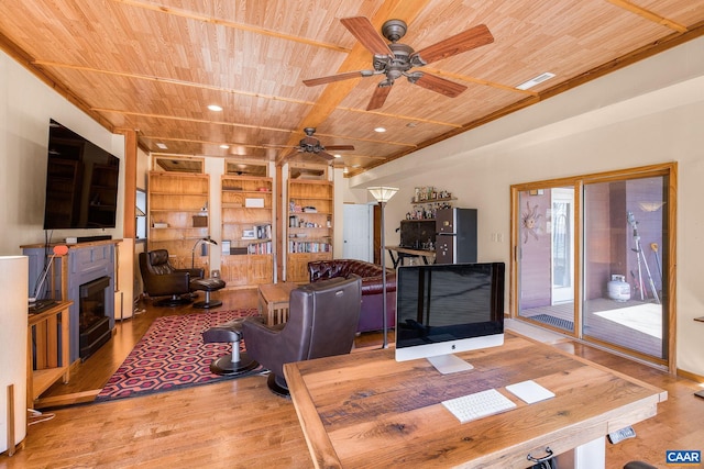 living area featuring wood ceiling, wood finished floors, a ceiling fan, a fireplace, and built in shelves