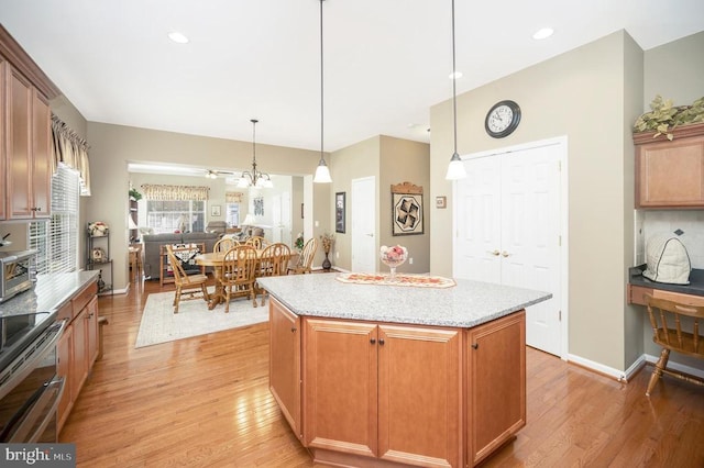 kitchen with light wood finished floors, a kitchen island, range with two ovens, and hanging light fixtures