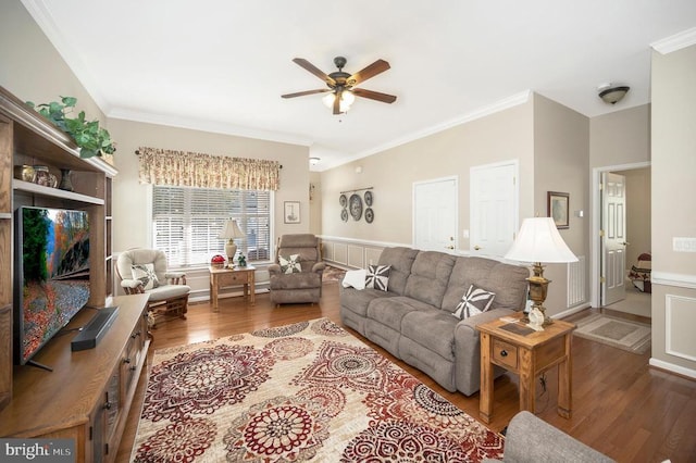 living area with a ceiling fan, wood finished floors, ornamental molding, and a wainscoted wall