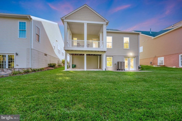 back of house with central AC, a yard, a balcony, and a garage